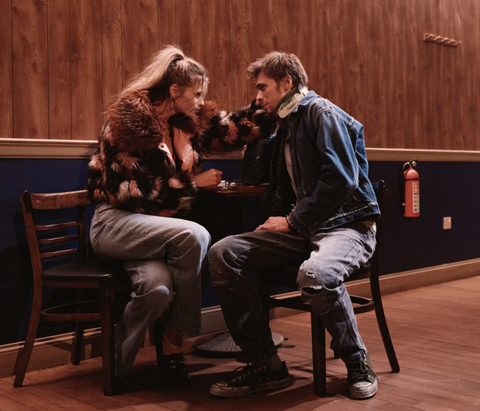 A woman and a man sitting at a table and holding each other's faces