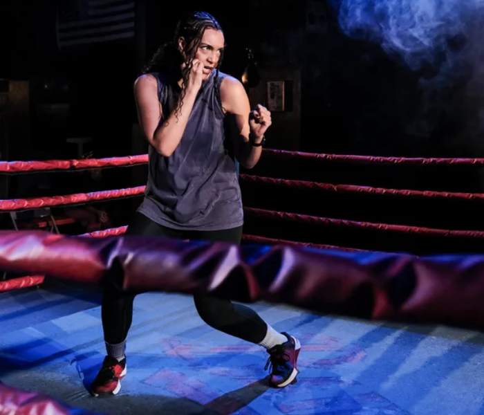 A woman in the boxing ring training under purple light